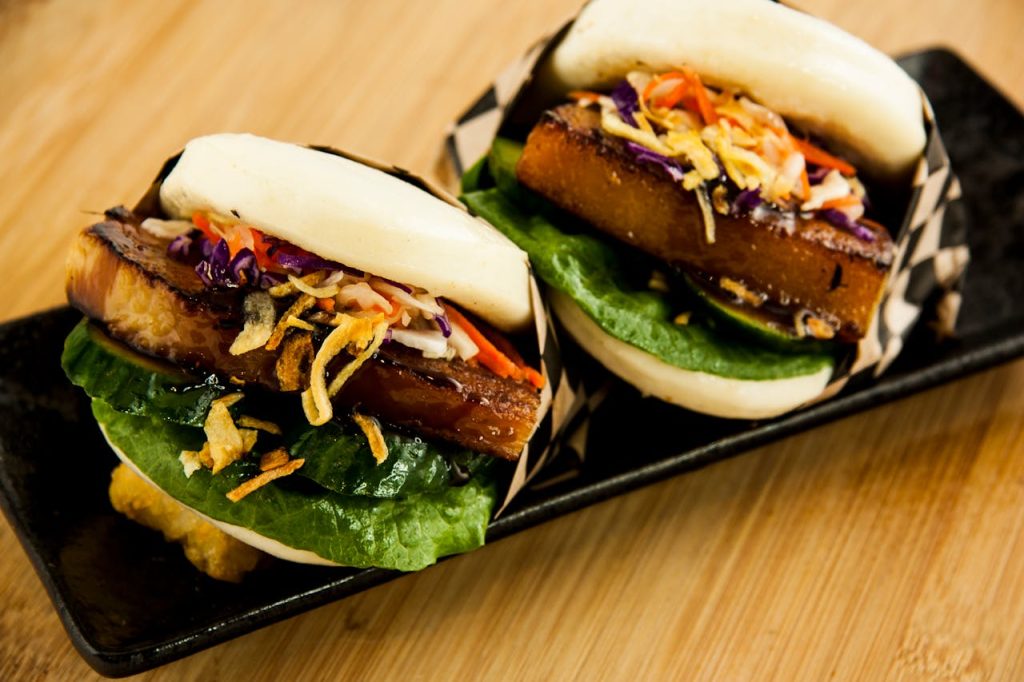 Delectable pork buns topped with vibrant vegetables in a close-up food photography shot.