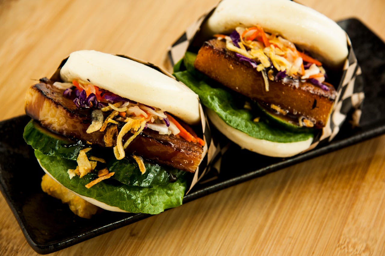 Delectable pork buns topped with vibrant vegetables in a close-up food photography shot.